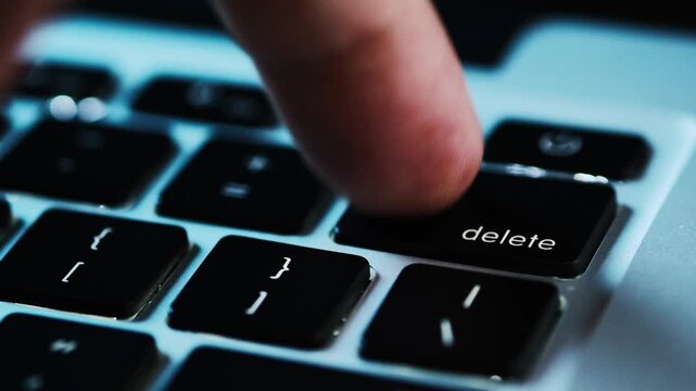 Finger of the computer user, he presses the delete button on the computer keyboard	