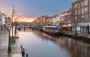 Historic canal with boats and buildings in the city of Leiden in the Netherlands at sunset
