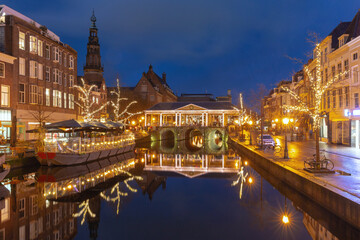 Fototapeta premium Corn Bridge and canal in Leiden Netherlands with Christmas lights and reflections at sunset