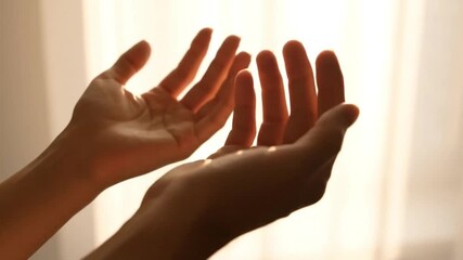 Close-up of human hands gently held together, illuminated by soft golden light