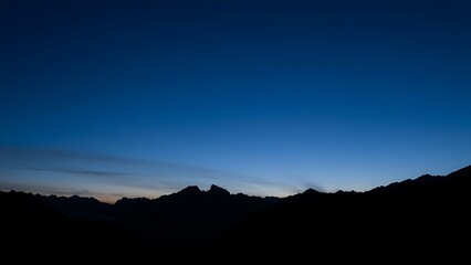 Majestic mountain peaks silhouetted against a twilight sky with a natural glow.