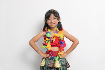 5-year-old Latina girl with brown hair enjoys learning to dance Hawaiian, wearing a colorful skirt and leis, and shows off her moves