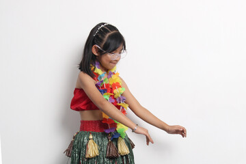 5-year-old Latina girl with brown hair enjoys learning to dance Hawaiian, wearing a colorful skirt and leis, and shows off her moves