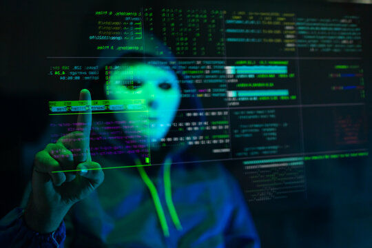 Masked hacker hacking computer. anonymous hacker wearing mask and black hoodie in dark room. online scam and cyber security threat.