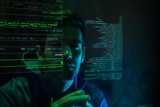 Masked hacker hacking computer. anonymous hacker wearing mask and black hoodie in dark room. online scam and cyber security threat.