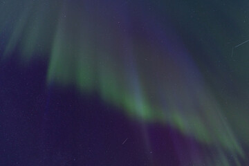 Curtains of green light and magenta hues merge in the vertical display of the Northern Lights, highlighting the densely scattered stars in the dark sky