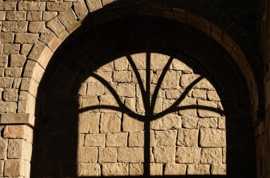 Shadow of a decorative arched window cast upon an old stone wall - Powered by Adobe