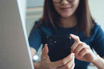 Young asian woman using smartphone and laptop for online shopping or digital banking, social media networking. Casual business woman surfing the internet, remote working at home office, closeup