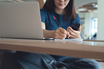 Young asian woman sitting on the floor, using laptop and smartphone, online working at home office. Casual business woman, freelancer remote working from cafe. Digital nomad lifestyle