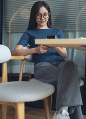 Close up, young asian woman sitting at table using mobile phone for online shopping, digital...