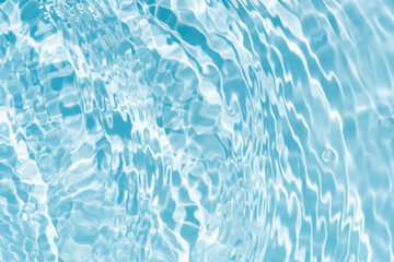 Blue water with ripples on the surface. Defocus blurred transparent blue colored clear calm water surface texture with splashes and bubbles. Water waves with shining pattern texture background.