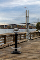 Fototapeta premium Public Pier With Binocular Viewer Over the River, Construction Bridge in New Westminster, BC