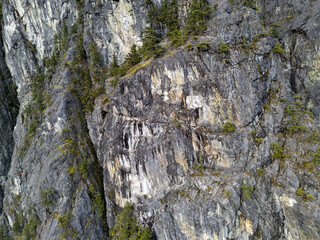 Steep Rocky Cliffs With Sparse Trees Tower Over Rugged Mountain Landscape in BC, Canada