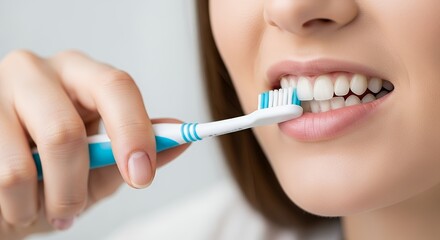 Close-up of a Young Woman Brushing Healthy White Teeth with a Blue and White Toothbrush for Oral Hygiene