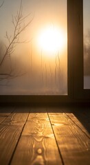Sunlight streaming through a foggy window casting warm glow on wooden floor with silhouette of a leafless tree branch outside during sunset