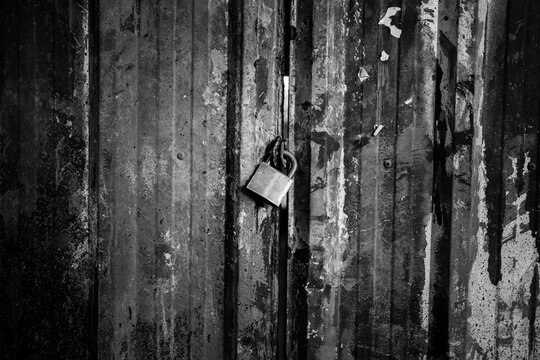 A lock is hanging from a rusty metal door