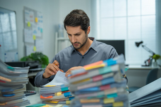 Hispanic businessman stressed over account mistakes, overwhelmed, tired, and facing deadlines in a busy office setting.
