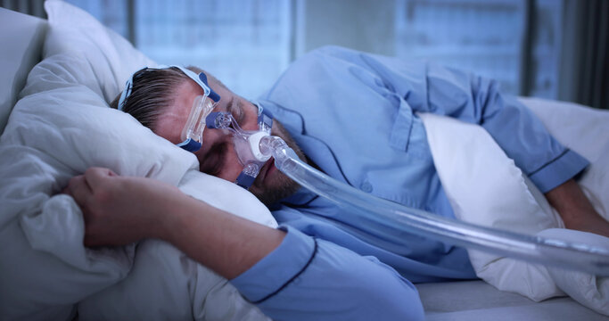 Man Wearing CPAP Machine Mask For Sleep Apnea Disorder Treatment