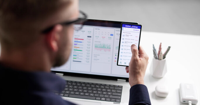 Young Man Using Smartphone App To Manage Online Budget And Finances