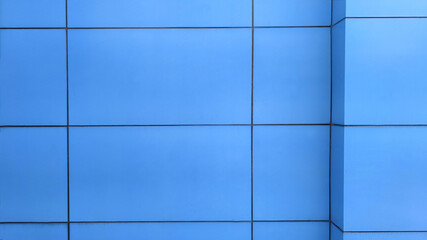 a modern building facade featuring blue square panel. blue color and are arranged in a grid pattern separated by dark vertical and horizontal lines