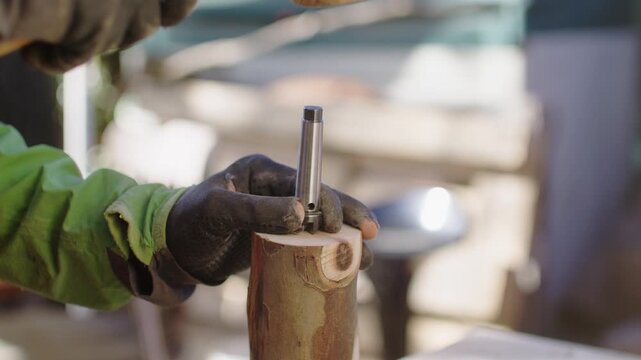 Hammering wooden mallet on metal with precision in sunny workshop