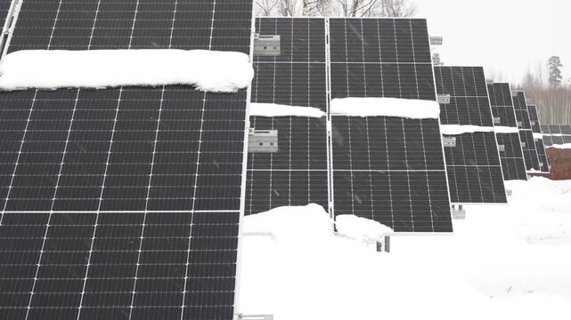 Snow covered solar panel array with winter weather conditions outside view.