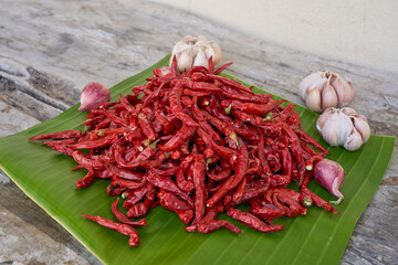 Red dried chilies are stacked on top of green banana leaves.
