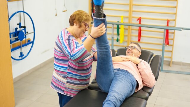 Physiotherapist assisting man with prosthetic leg during rehabilitation - Powered by Adobe
