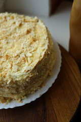 Beautifully layered macro cake topped with crunchy flakes displayed on a wooden serving platter in a cozy kitchen setting