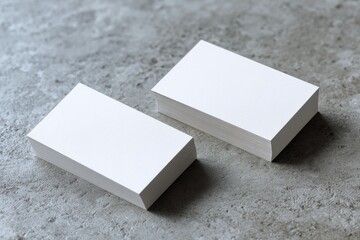 Two stacks of blank business cards on a gray stone surface
