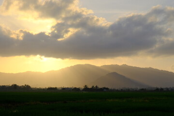 Sunrays Illuminating Misty Hills Over Paddy Fields