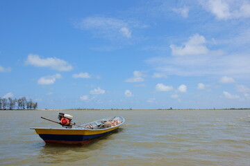 Naklejka premium Traditional fishing boat floating on river under bright sky