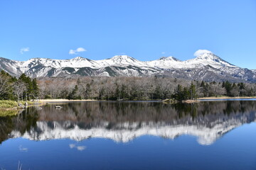 Fototapeta premium Snow-covered mountains reflected on calm sea in Shiretoko, Hokkaido, Japan