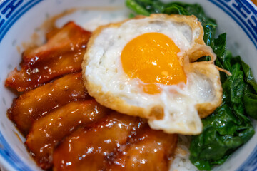 Barbecued red pork in sauce with rice, and fried egg on the top.