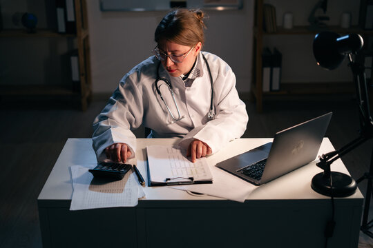 Doctor use calculator working during night shift. Healthcare and medical concept. - Powered by Adobe