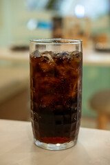 A glass of Cola on the table with bokeh background
