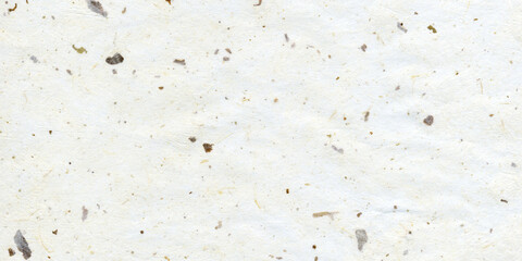 A close-up texture of natural handmade paper with small organic fibers and speckled particles embedded throughout the surface. The paper appears soft, slightly rough, and earthy, featuring subtle vari