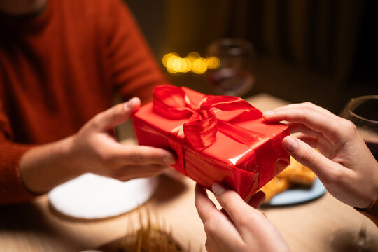 Valentine's Day concept. Man gives to his woman gift box with red ribbon - Powered by Adobe