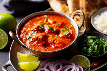 Authentic Indian feast: chicken tikka masala with rice, naan, lime and spices. Grey background. Close up.