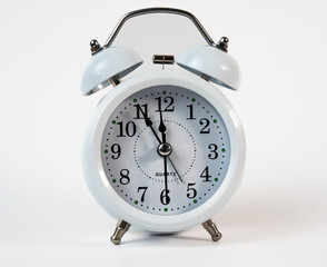Classic white alarm clock showing time close to midnight. Perfect for New Year countdown or time management themes. 