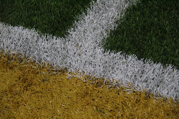 Close-up of colorful turf intersection with green, white, and yellow lines. Ideal for sports, field design, or athletic-themed visual content