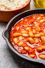 Baked bean dish in cast iron pan on vintage background