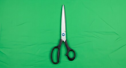 A pair of black-handled scissors placed on a bright green textured background suitable for craft or sewing projects