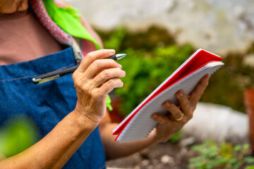Senior woman writing notes in garden notebook