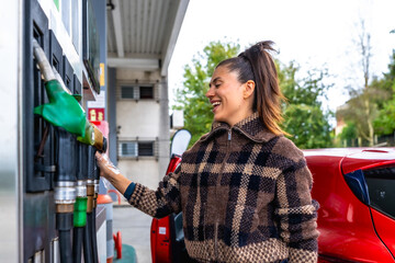 Woman refueling car at gas station pump smiling