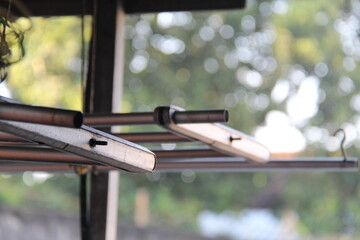 Close-up of a metal clothes drying rack outdoors with natural bokeh background. Represents laundry, domestic chores, and simple living in a home setting