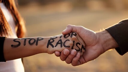 Two hands shaking with stop racism written on one arm