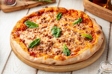 Freshly baked Italian pizza with tomato sauce, spinach leaves, and melted cheese on a wooden board