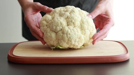 slicing cauliflower head on wooden cutting board - Powered by Adobe