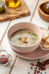 Bowl of creamy mushroom soup with herbs and oil served with crispy croutons on pink plate